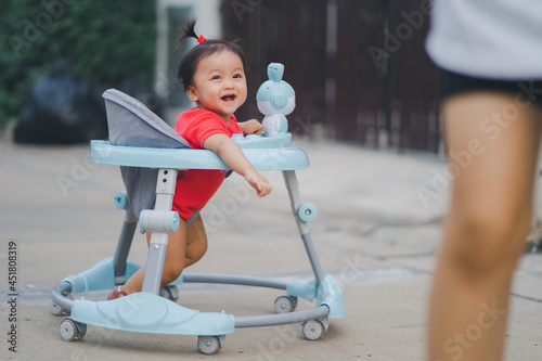 child in happy time child running with mom in outdoor at road village to practice balance walk in development according to the age of the child on Baby car to help practice walking