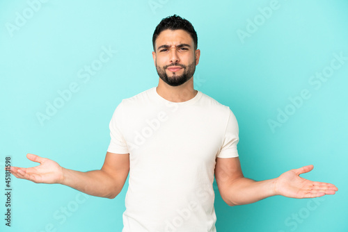 Young arab man isolated on blue background having doubts © luismolinero