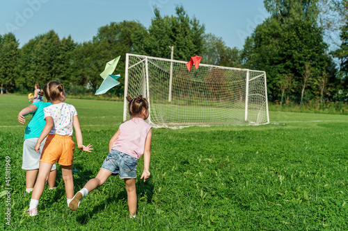 Small children, preschoolers launch a paper plane into the air in the park on a sunny summer day. Outdoor games in the fresh air. A fun childhood. An active game. Children Protection Day.