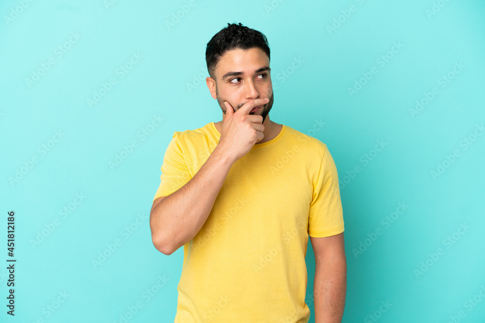 Young arab man isolated on blue background having doubts and with confuse face expression Young arab man isolated on blue background having doubts and with confuse face expression