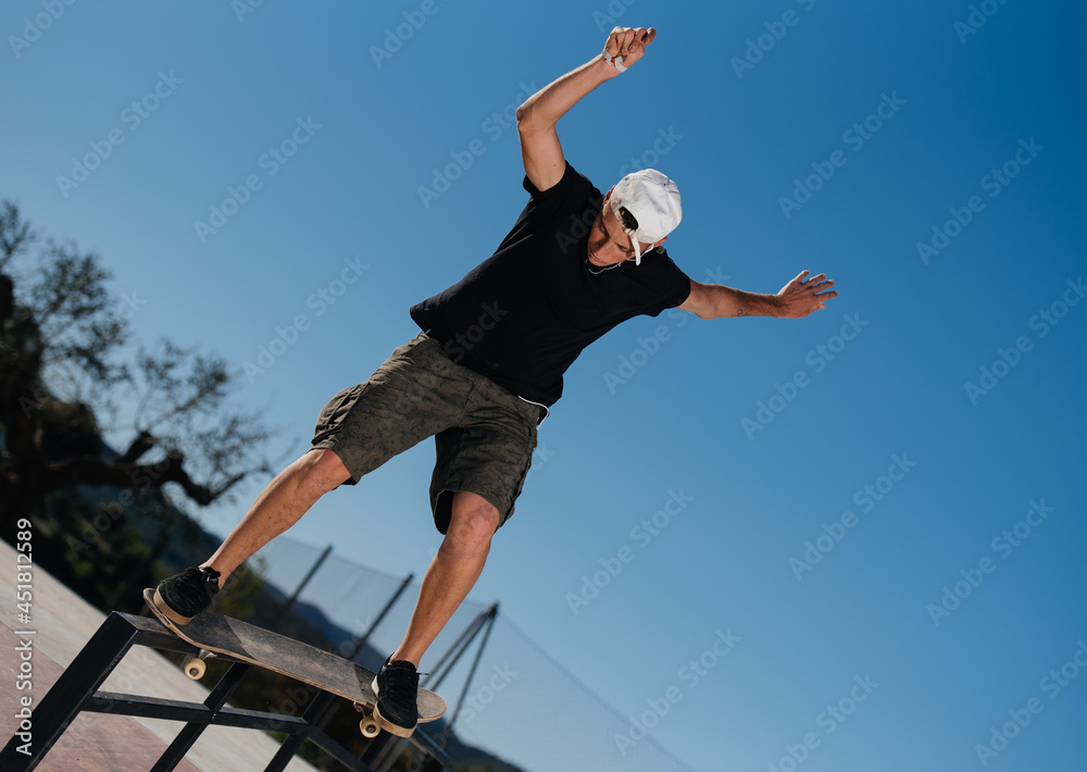 Young man jumping a railing on a skateboard. Stock Photo Adobe Stock
