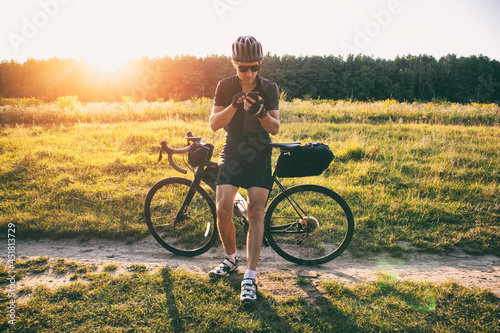The bike traveler got lost in the middle of field and looking for the route in the smartphone