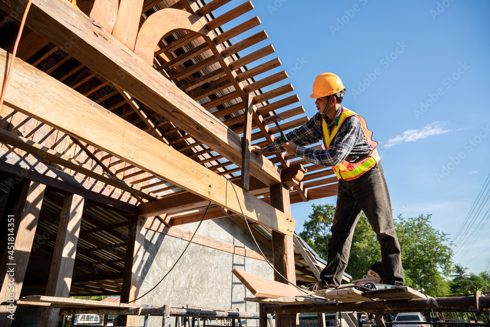 A male roofer carpenter working on roof structure on construction site
