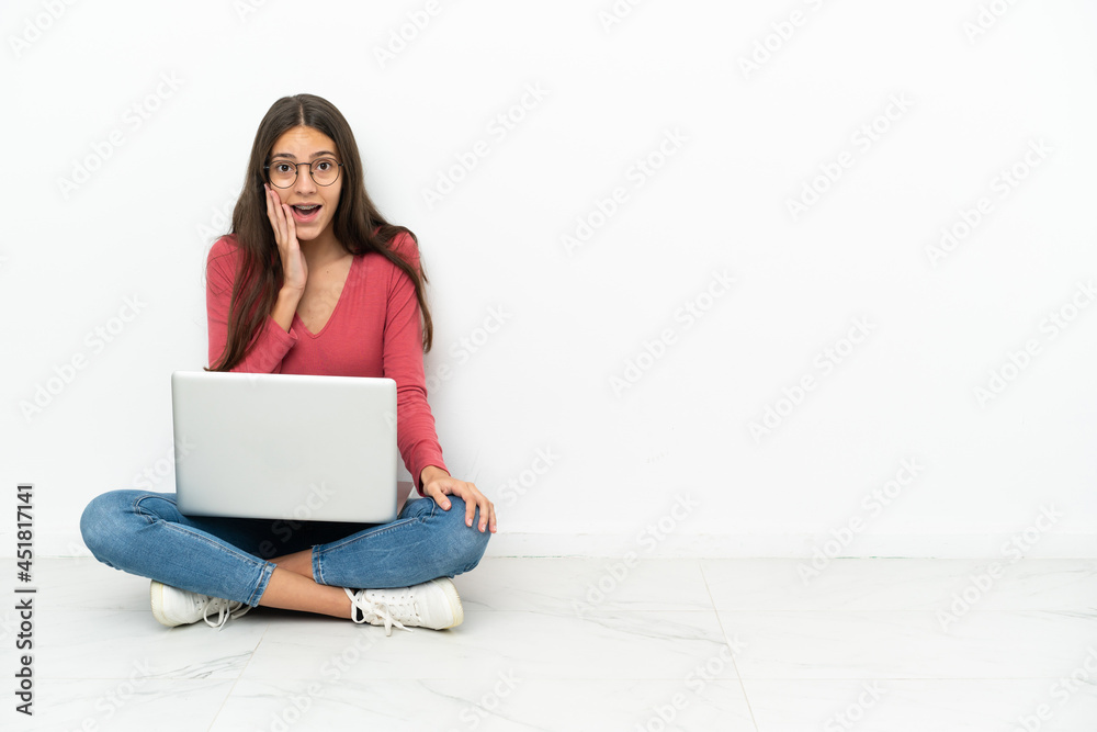 Young French girl sitting on the floor with her laptop with surprise and shocked facial expression Young French girl sitting on the floor with her laptop with surprise and shocked facial expression