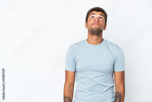 Young handsome Brazilian man isolated on white background and looking up