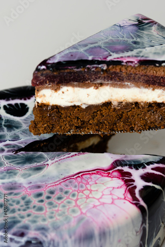 Close-up mousse cake covered black  red and white mirror glaze. French dessert. Frozen mirror icing on the cake. Baking and confectionery concept.