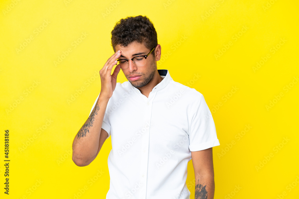 Young handsome Brazilian man isolated on yellow background with headache Young handsome Brazilian man isolated on yellow background with headache