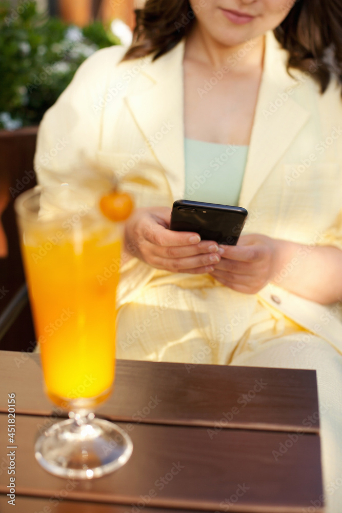 Woman holding a mobile phone at the restaurant with cocktail on the table Woman holding a mobile phone at the restaurant with cocktail on the table