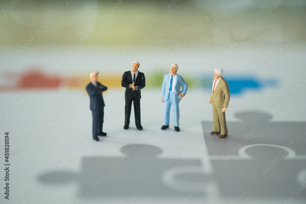 A group of businessmen standing on the white paper with a jigsaw. The plan the new strategy for next year. A group of businessmen standing on the white paper with a jigsaw. The plan the new strategy for next year.