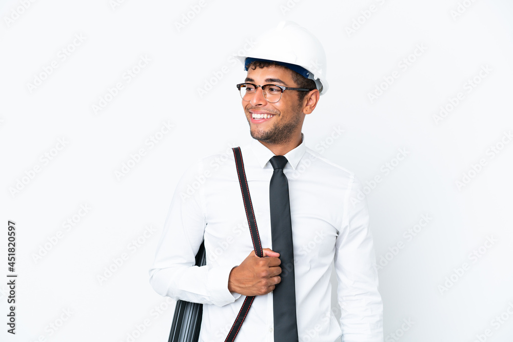Architect brazilian man with helmet and holding blueprints looking to the side and smiling Architect brazilian man with helmet and holding blueprints looking to the side and smiling