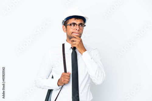 Architect brazilian man with helmet and holding blueprints having doubts and thinking