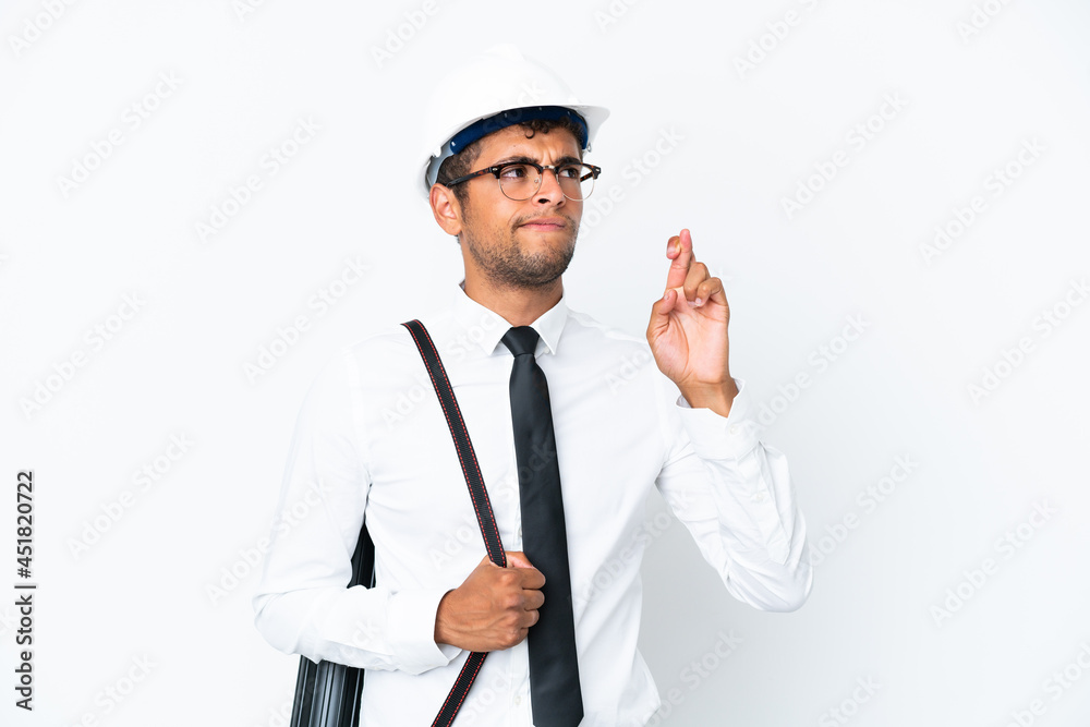 Architect brazilian man with helmet and holding blueprints with fingers crossing and wishing the best