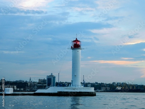  Red and white lighthouse in sea at sunset, copy space.Black sea. Summer seascape with light house. Lighthouse at sunset. The blue sea. 