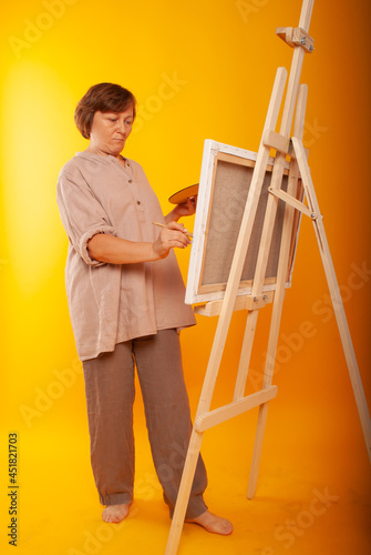 A woman artist of European appearance draws on an easel, canvas with kit and paints. Place for text, teacher drawing lesson at school