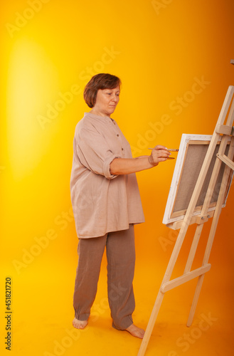 A woman artist of European appearance draws on an easel, canvas with kit and paints. Place for text, teacher drawing lesson at school