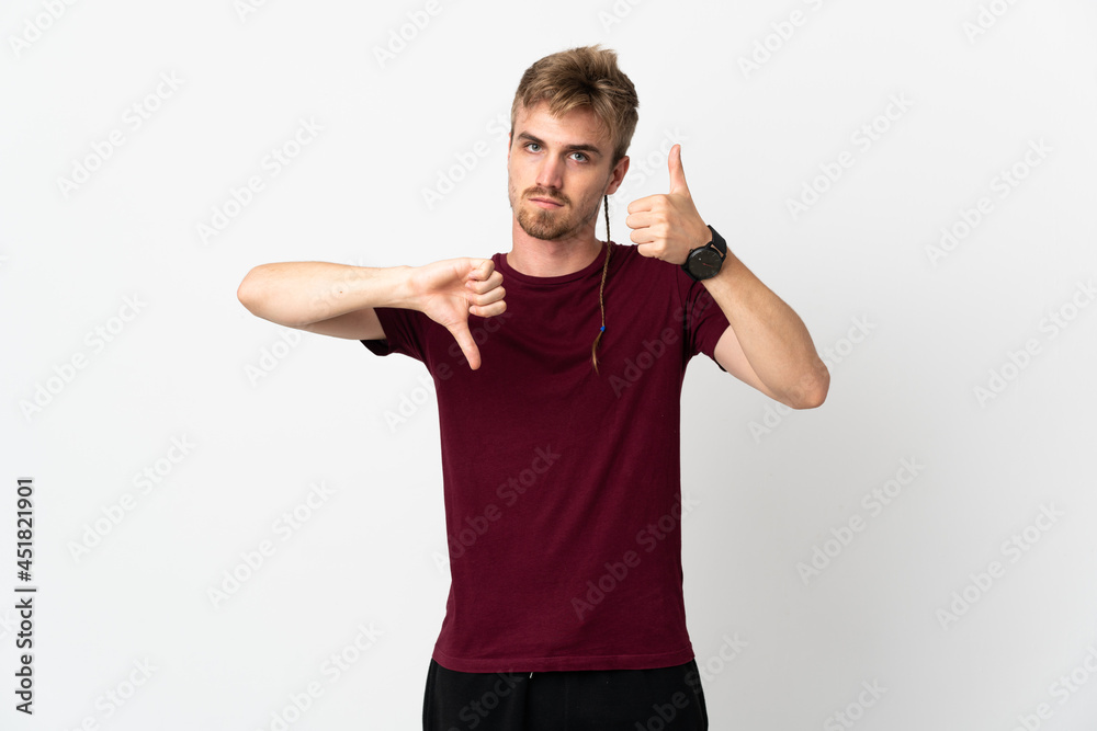 Young handsome man isolated on white background making good-bad sign. Undecided between yes or not Young handsome man isolated on white background making good-bad sign. Undecided between yes or not