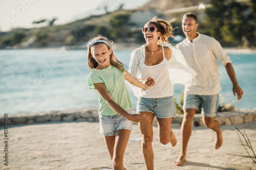 Family Having Fun While Walking Near The Sea And Enjoying Summer Vacation
