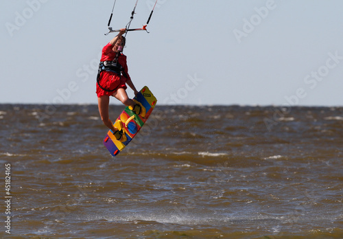 Kiter girl in red dress performes a  trick photo