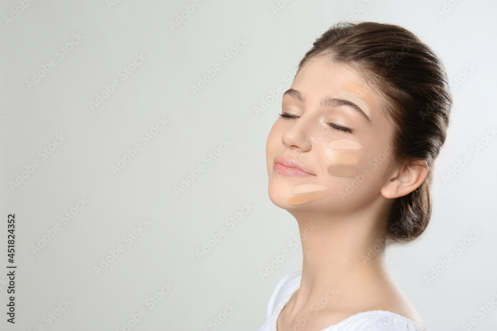 Beautiful girl on light grey background. Using concealers and foundation for face contouring Beautiful girl on light grey background. Using concealers and foundation for face contouring