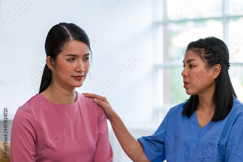 Stressed Asian woman sitting and discussing with nurse at the hospital. Psychologist or female practitioner discussing treatment with woman patient and comforting
