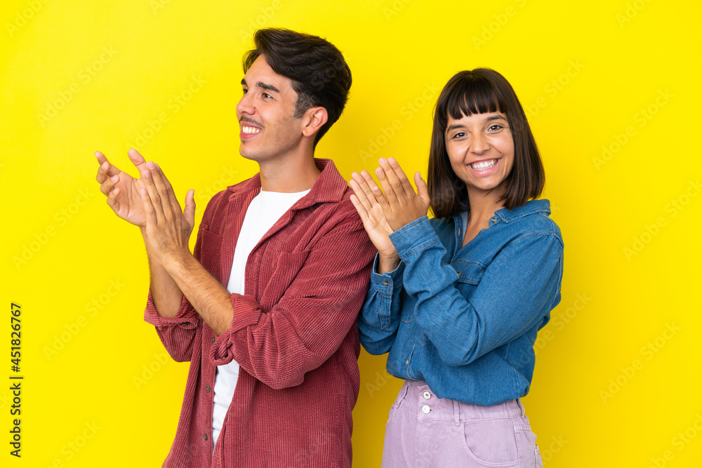 Young mixed race couple isolated on yellow background applauding after presentation in a conference Young mixed race couple isolated on yellow background applauding after presentation in a conference