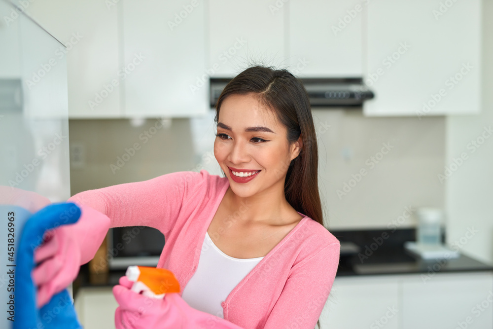 Young asian woman cleaning the kitchen with detergent spray. Young asian woman cleaning the kitchen with detergent spray.