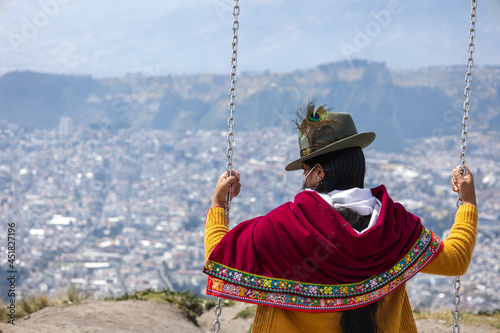 An Ecuadorian indigenous woman on a swing, at an extremely high altitude looking down at Quito, Ecuador