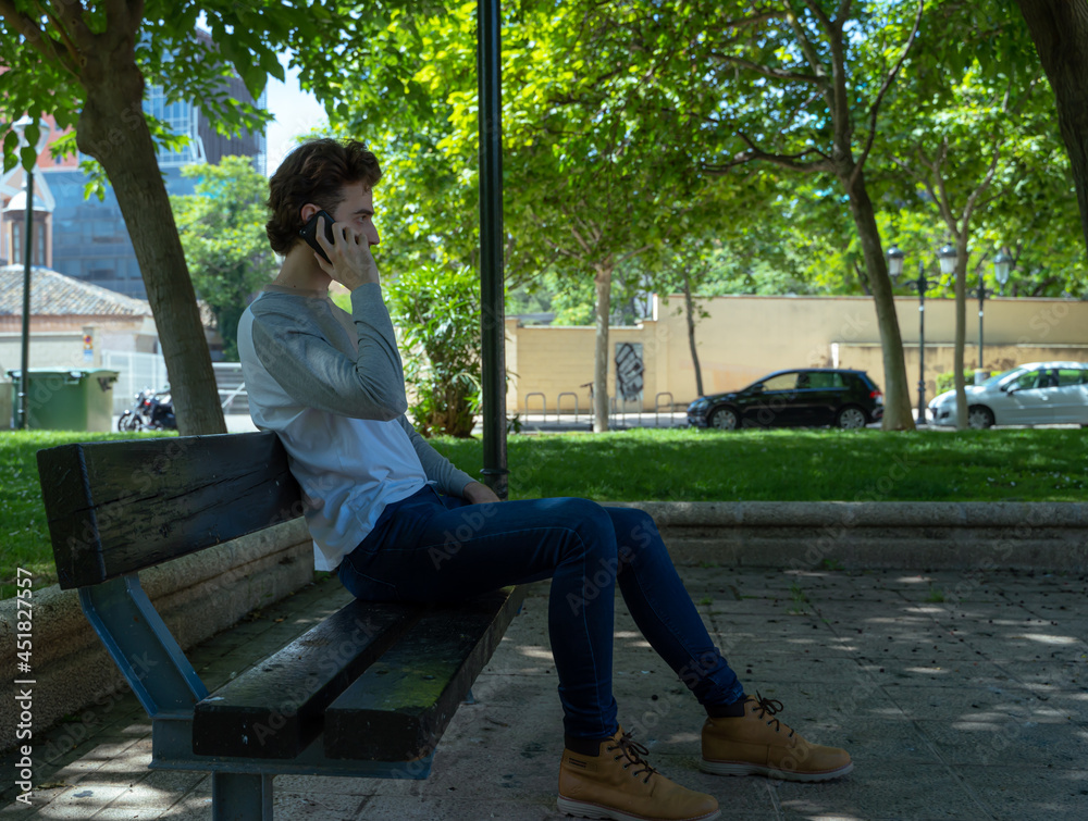 man talking on the phone, sitting in the park
