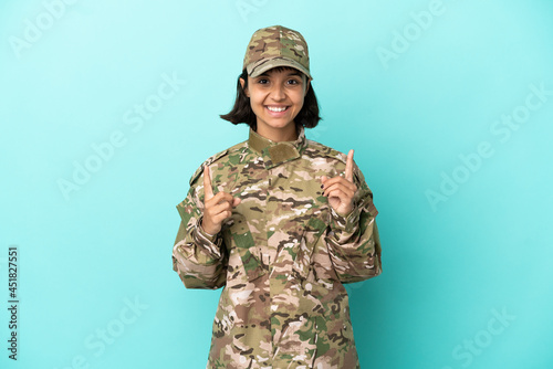 Military mixed race woman isolated on blue background pointing up a great idea