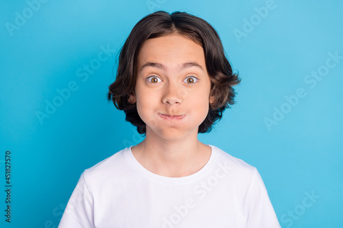 Photo of funky foolish schoolboy inflate cheeks hold breath wear white t-shirt isolated blue color background photo