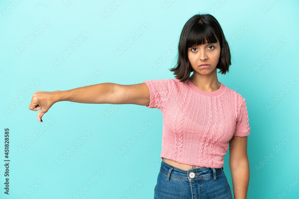 Young mixed race woman isolated on blue background showing thumb down with negative expression Young mixed race woman isolated on blue background showing thumb down with negative expression