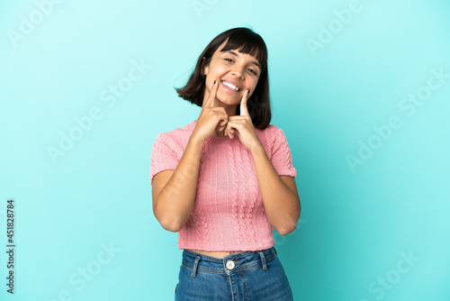 Young mixed race woman isolated on blue background smiling with a happy and pleasant expression