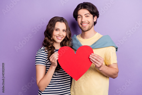 Photo of cute sweet lovers dressed casual outfit holding big red heart smiling isolated purple color background