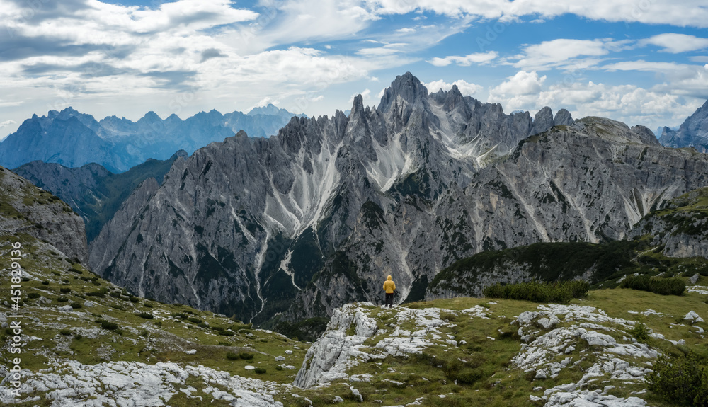 Obraz premium Man hiker standing and admiring stunning beauty of impressive jagged peaks of Cadini di misurina mountain group in Dolomites, Italy, part of Tre Cime di Levaredo national park