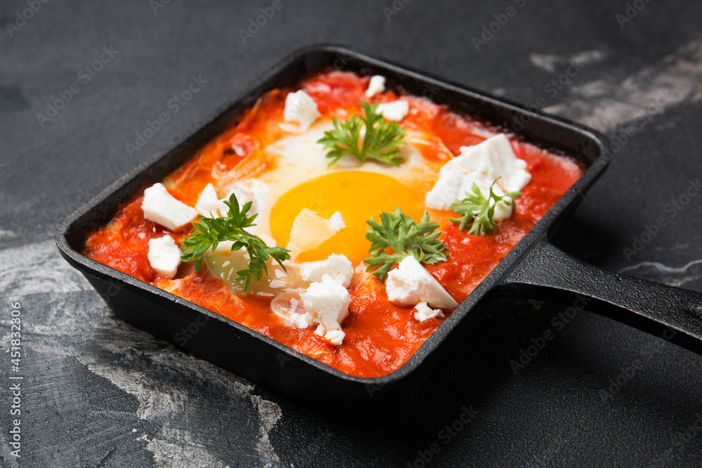 Fried eggs with tomatoes and cheese in a frying pan. Shakshuka, a Jewish dish.
Fried eggs with tomatoes and cheese in a frying pan. Shakshuka, a Jewish dish.