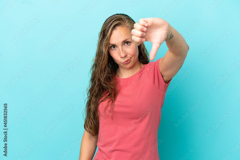 Young caucasian woman isolated on blue background showing thumb down with negative expression