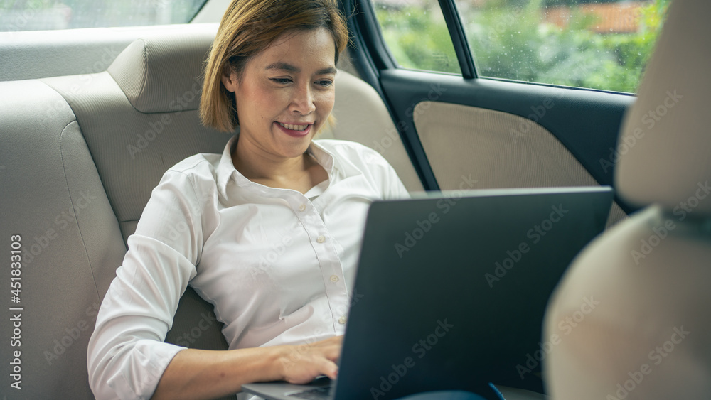 business woman using laptop for work in the backseat of the car business woman using laptop for work in the backseat of the car
