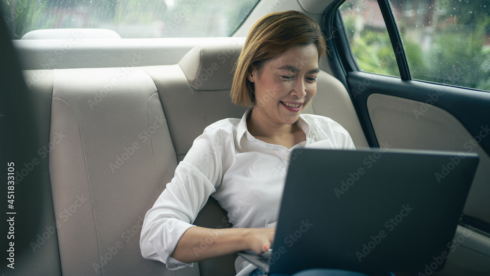 business woman using laptop for work in the backseat of the car business woman using laptop for work in the backseat of the car