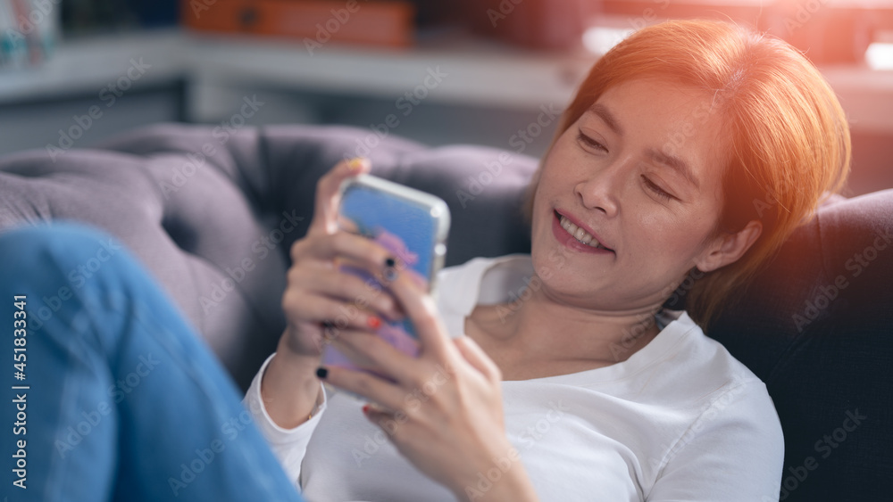 Asian woman using smartphone on sofa, at home, working at home concept Asian woman using smartphone on sofa, at home, working at home concept