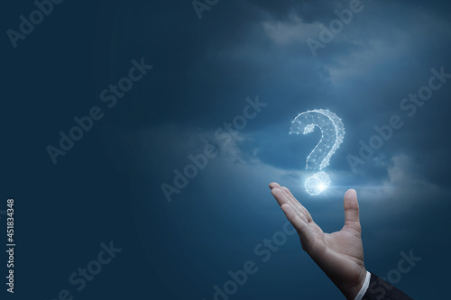 Businessman shows a hologram of a question mark on a blue background. photo