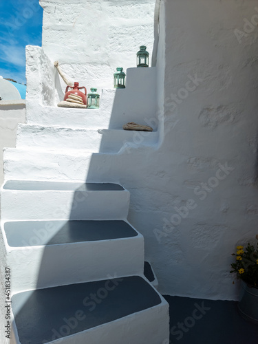 Whitewashed building empty narrow stone stairs at Kimolos island Greece. Vertical photo