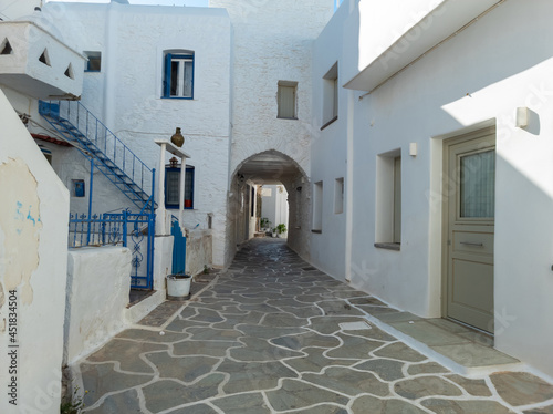 Cobblestone narrow alley whitewashed houses Kythnos island Cyclades Greece.