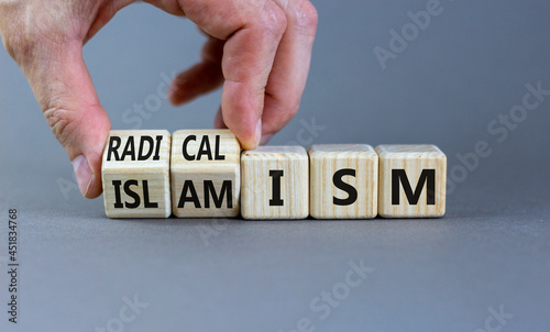 Radicalism or islamism symbol. Businessman turns cubes and changes the word 'radicalism' to 'islamism'. Beautiful grey background. Business, politic, radicalism or islamism concept. Copy space.