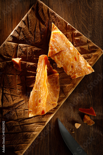 Pieces of aged cheese on a wooden Board with a knife. Italian hard cheese still life  top view. High resolution. 