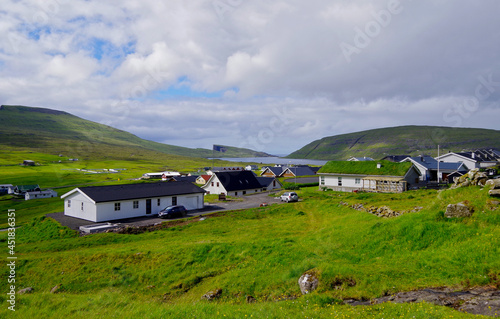 Panoramablick grüne Wiese Bucht auf Färöer Insel Varga mit Felsen Bergen skyline Stadt im Hintergrund - Cliffs and green Grass hills on Faroe Island Varga with rocks and panoramic landscape views	 photo