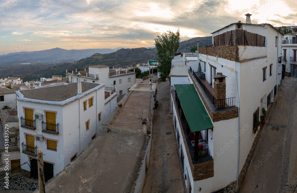Panoramic view from above of the houses of Laroles, mountains, sloping streets in a sunset