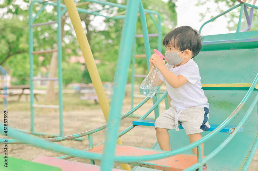 Little boy playing in the playground, the child is wearing a protective mask on the face during the quarantine of coronavirus, covid-19, virus protection. Little boy playing in the playground, the child is wearing a protective mask on the face during the quarantine of coronavirus, covid-19, virus protection.