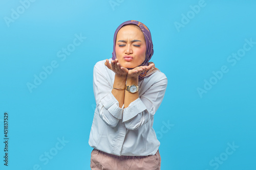 Beautiful Asian woman giving air kiss. isolated on blue background. Valentine's day concept. photo