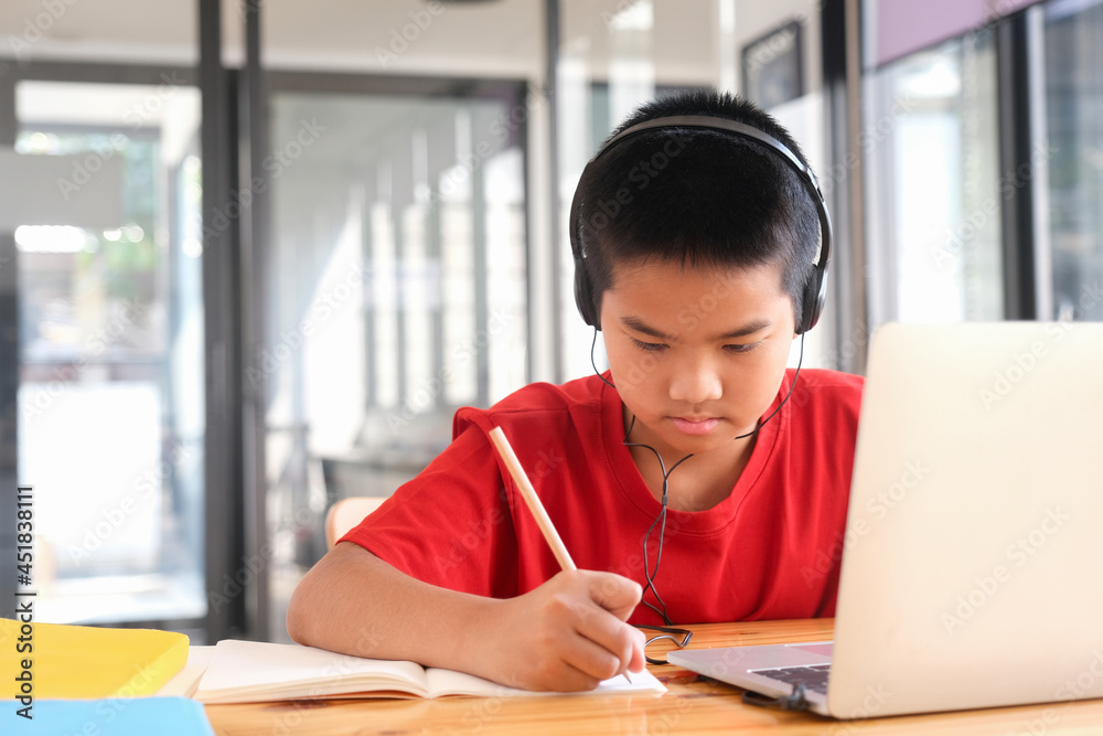 Young collage student using computer and mobile device studying online.