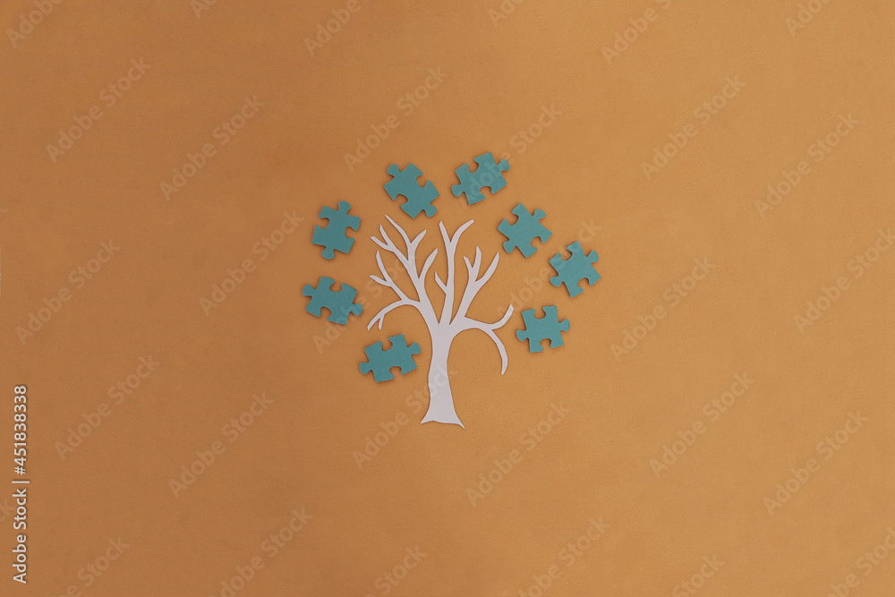 A tree, a crown of blue puzzles on a light brown background. Joint work, project. The result of the interaction.